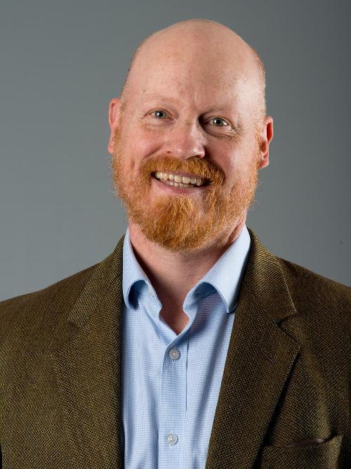 smiling man with beard in brown blazer